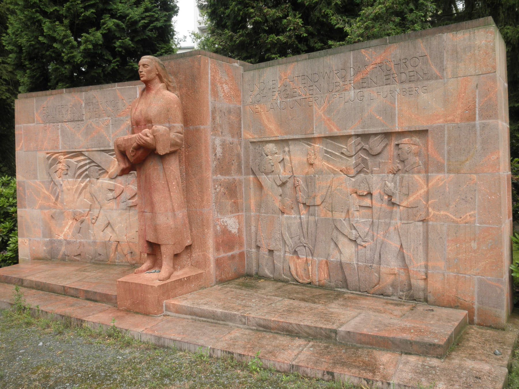 Denkmal für Bombenopfer aus rotem Stein mit zentraler Frauenfigur und seitlichen Reliefs auf Städtischer Friedhof Chemnitz